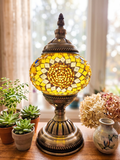 Decorative mosaic lamp on a table with plants and flowers in the background