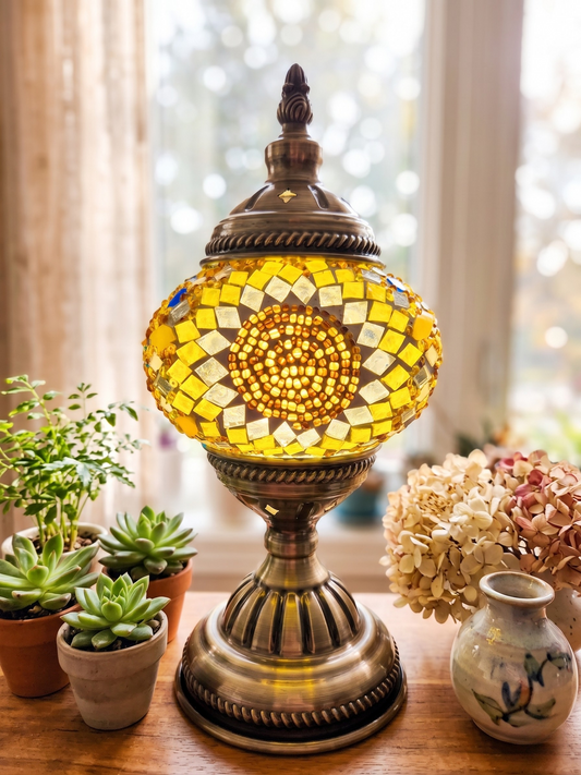 Decorative mosaic lamp on a table with plants and flowers in the background