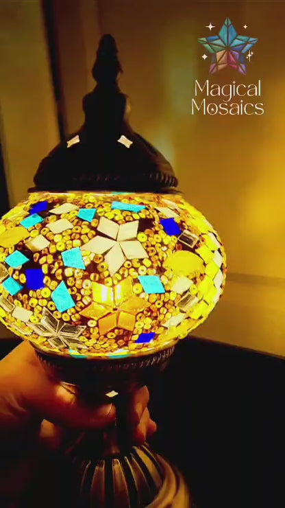 Video of decorative lamp with mosaic design held by a hand, blurred indoor background