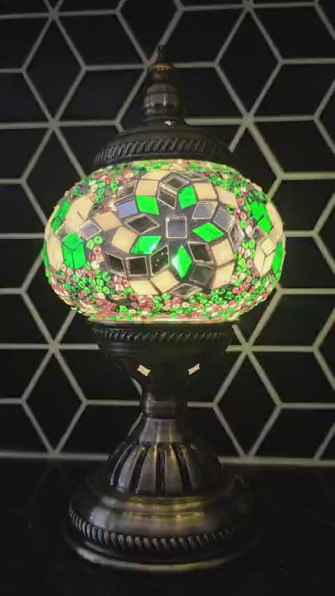 Decorative mosaic lamp video with green and silver design against a geometric black and white tiled wall.
