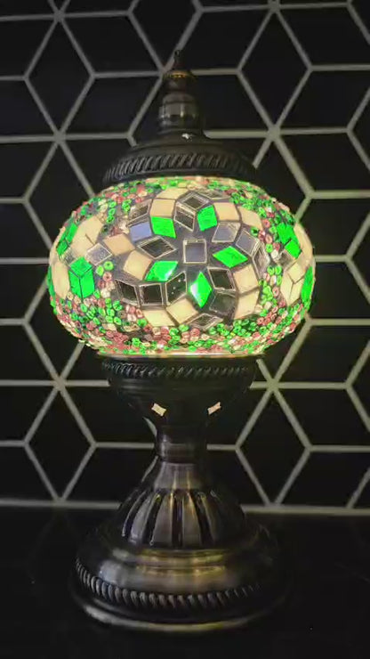Decorative mosaic lamp video with green and silver design against a geometric black and white tiled wall.